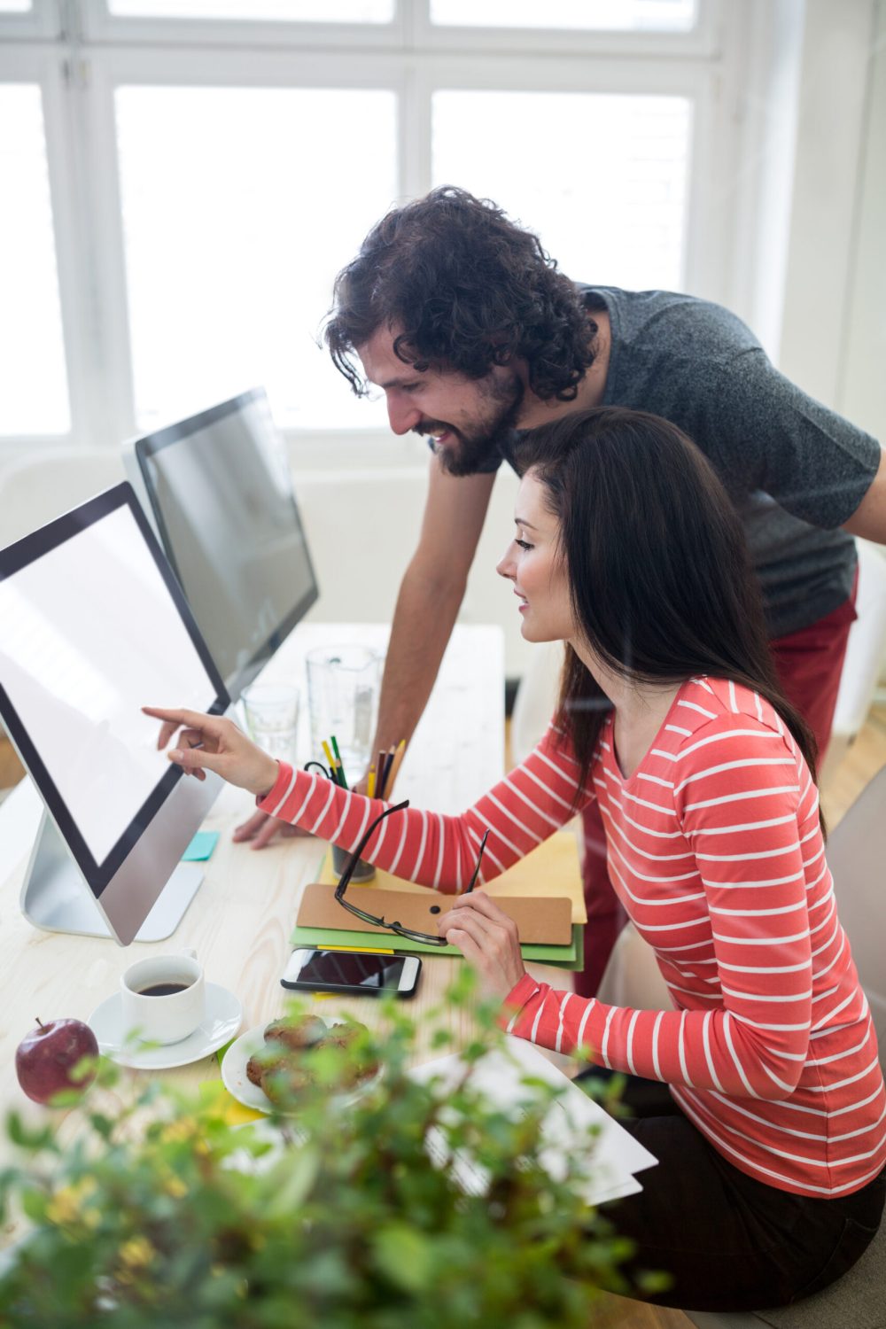 Male and female graphic designers interacting over computer in office